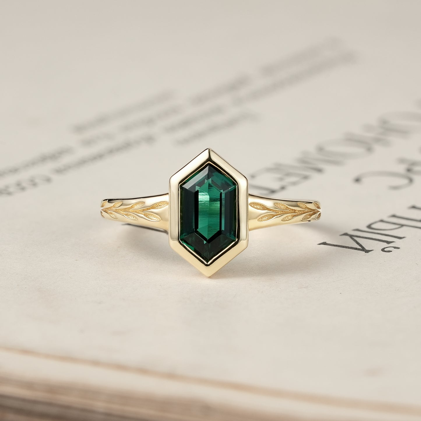 Hexagon emerald ring with a gold band featuring leaf designs