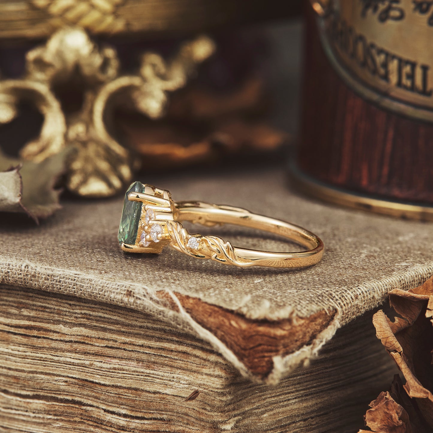 Side view of green sapphire leaf ring on textured gold band with moissanite accents.