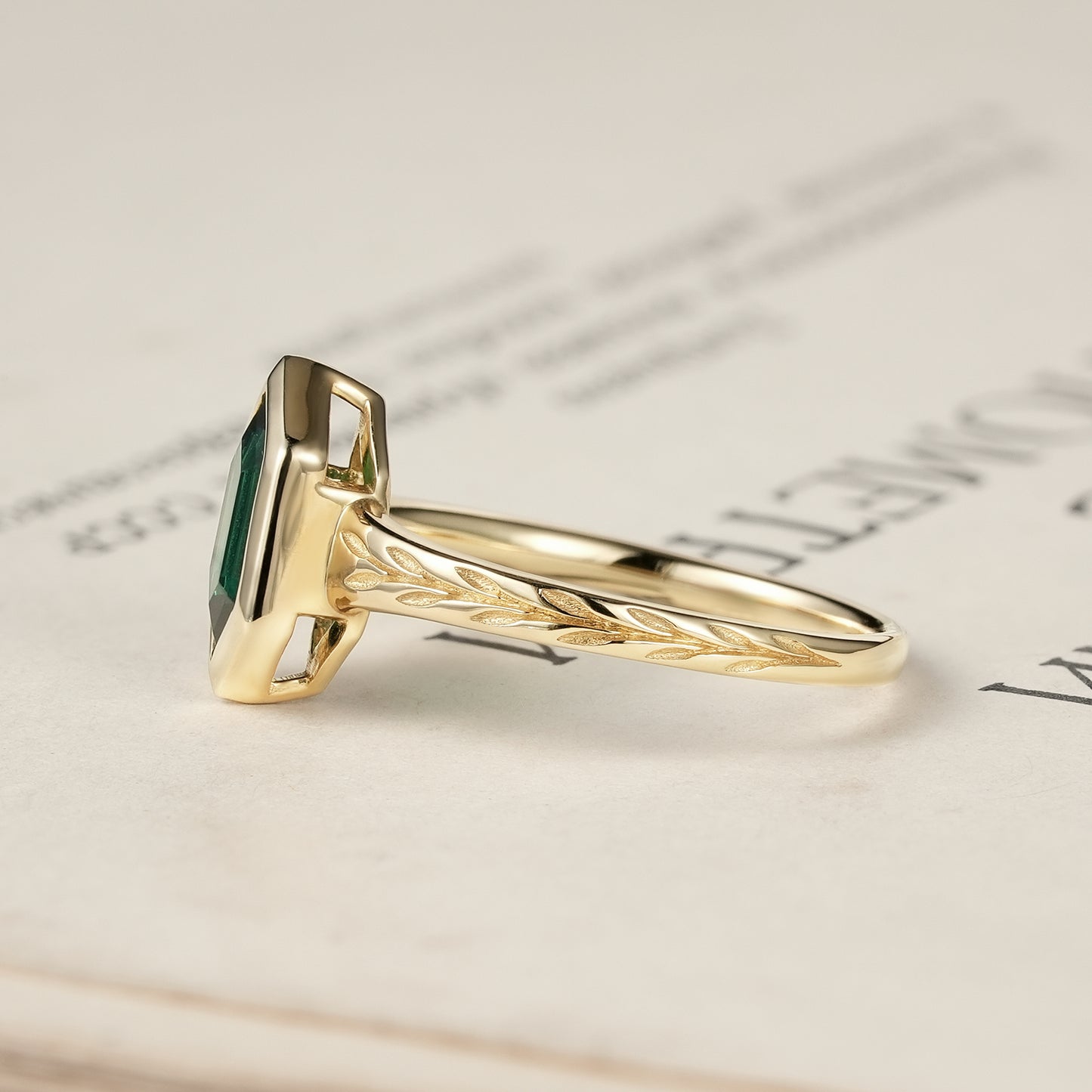 Side view of hexagon emerald ring with leaf details on gold band