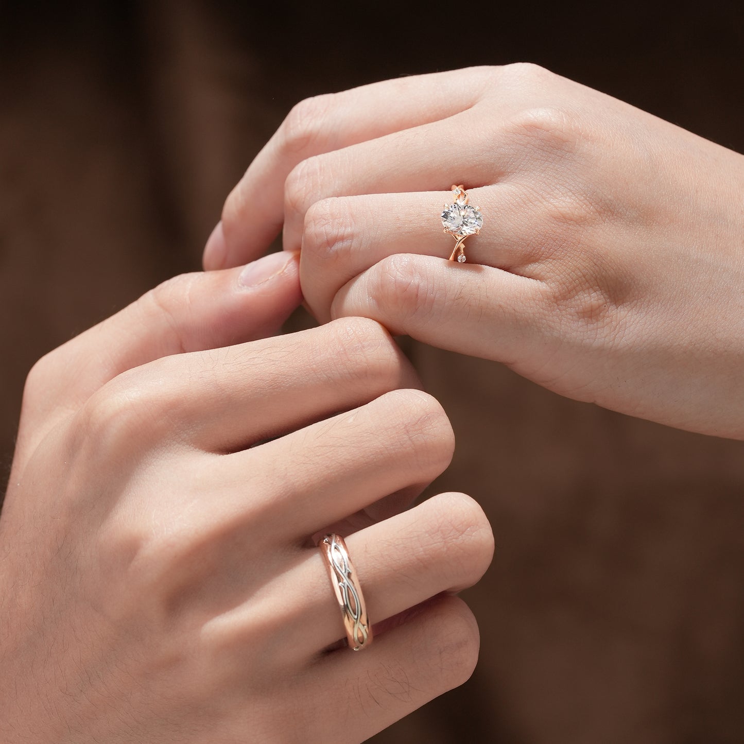 Couple wearing oval-cut moissanite vine engagement and wedding rings in gold.
