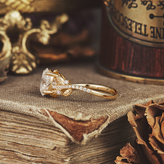 Elegant gold moissanite engagement ring with oval cut and nature-themed details.