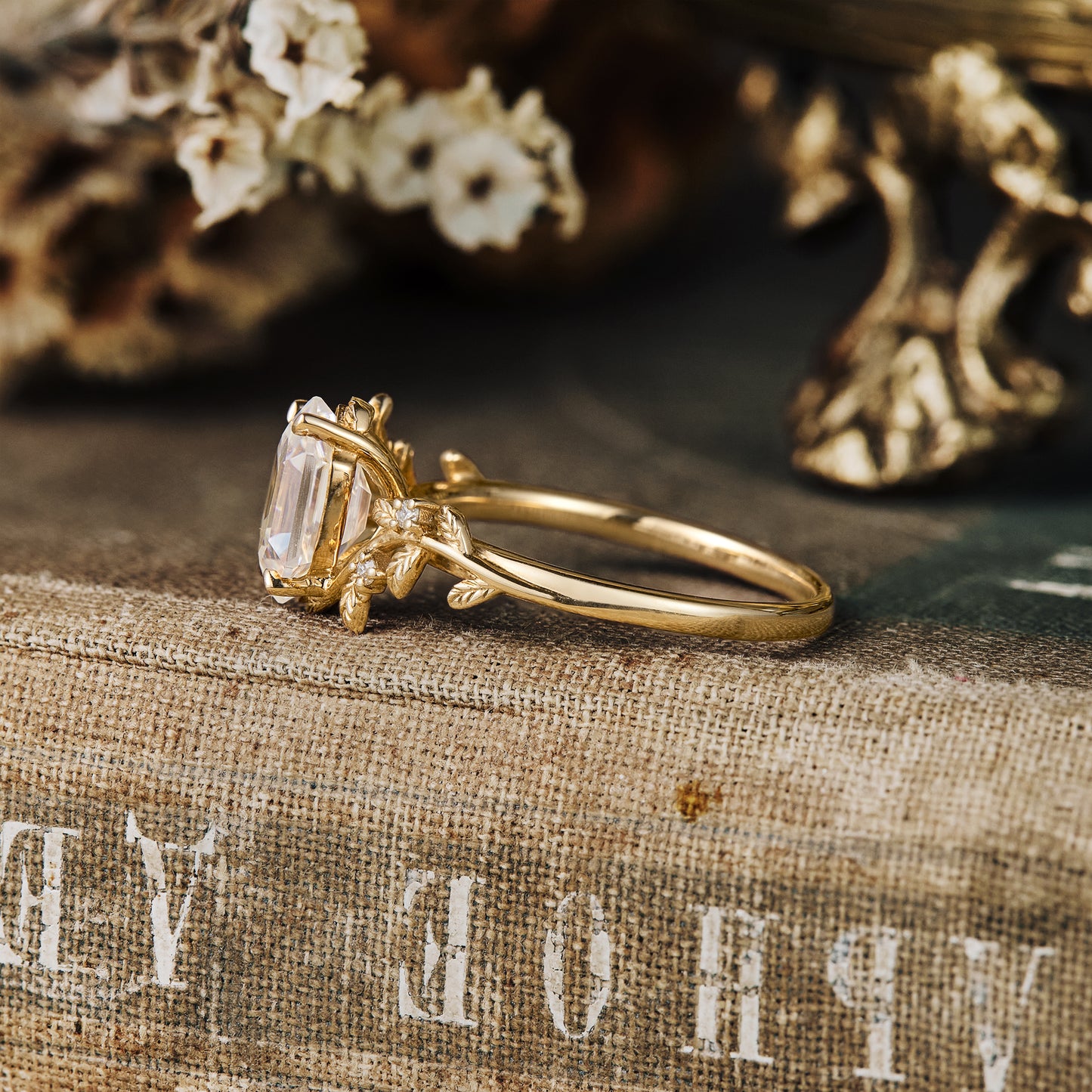 Leaf-inspired engagement ring with emerald-cut Moissanite set in gold band.