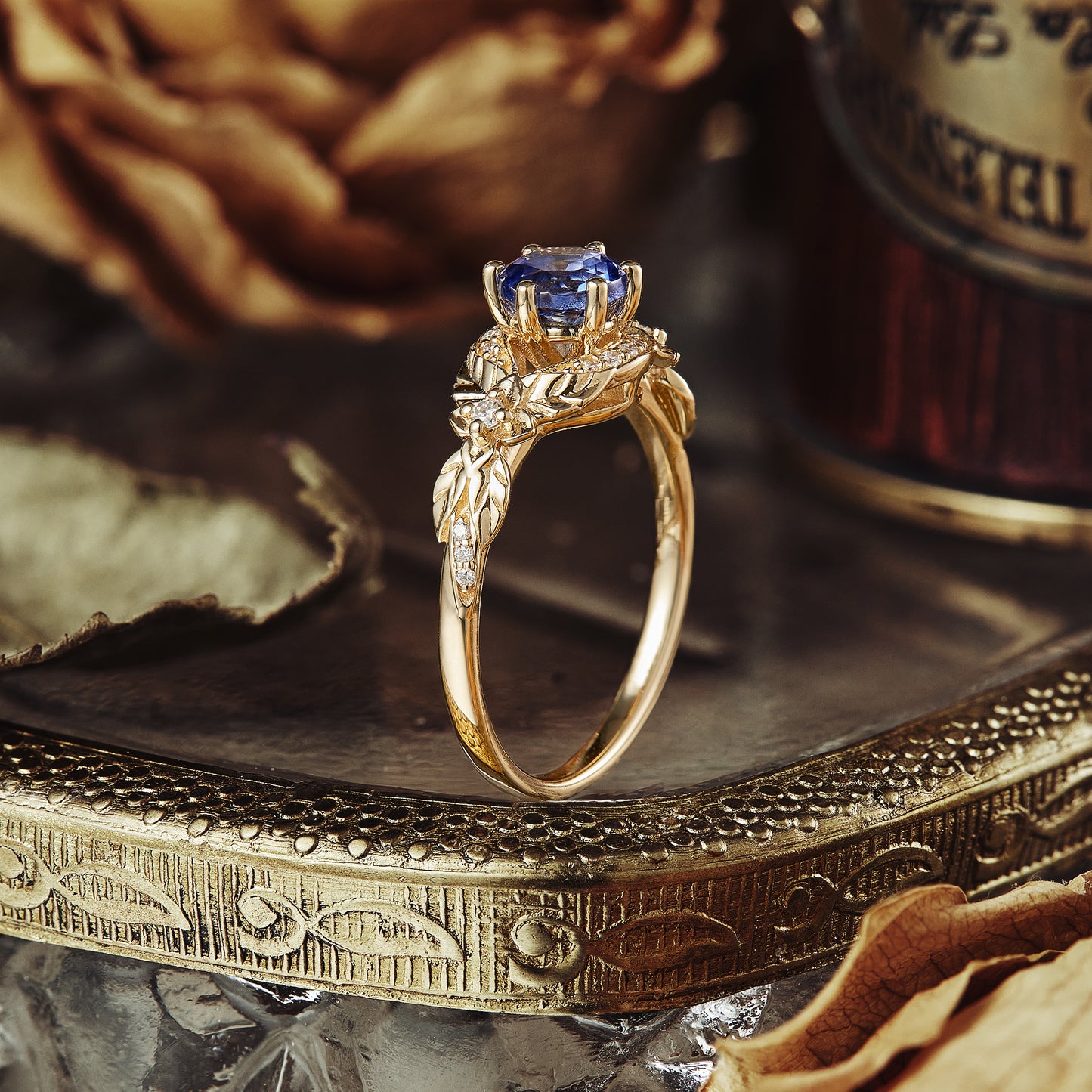 Nature-inspired yellow gold engagement ring with sapphire and leaf accents