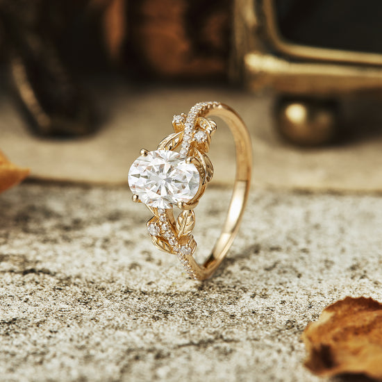 Oval-cut moissanite engagement ring with nature-inspired leaf details in gold.