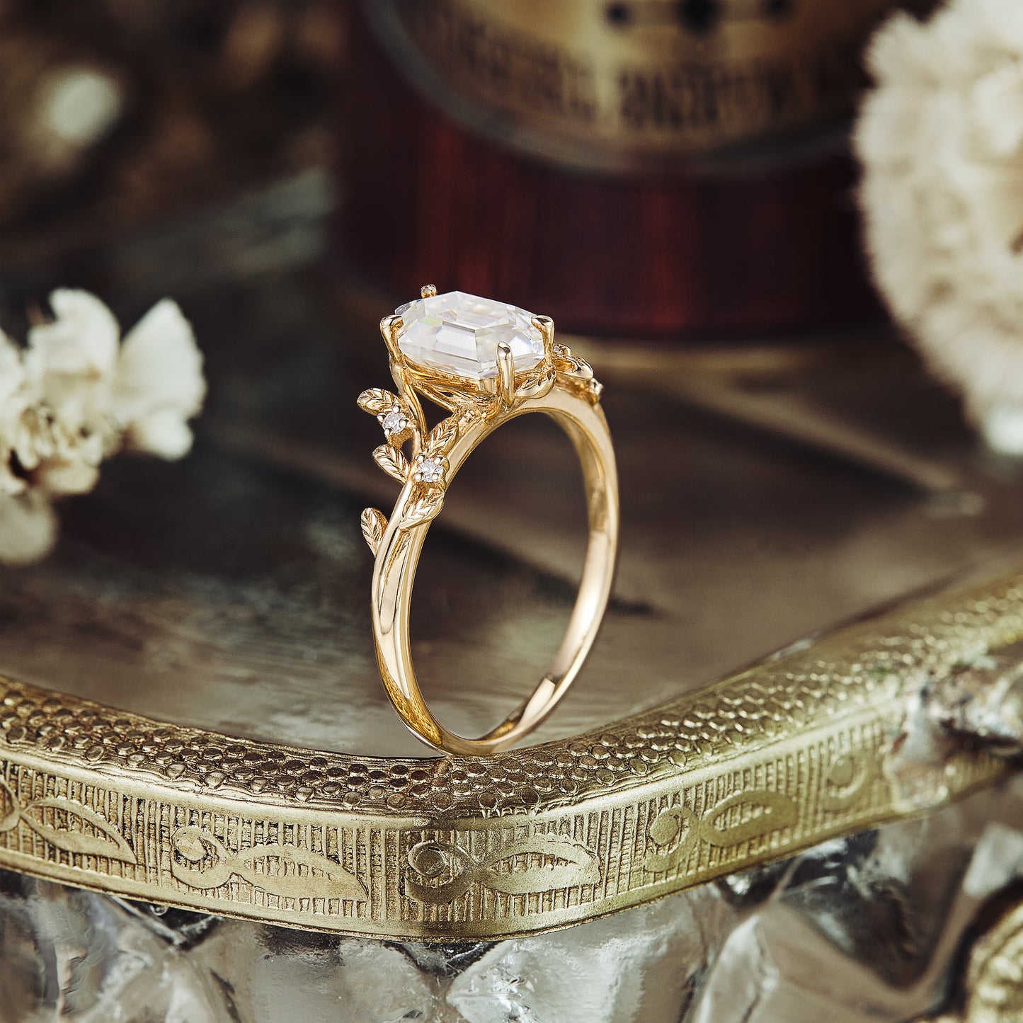 Gold leaf design engagement ring with emerald-cut Moissanite and floral accents.