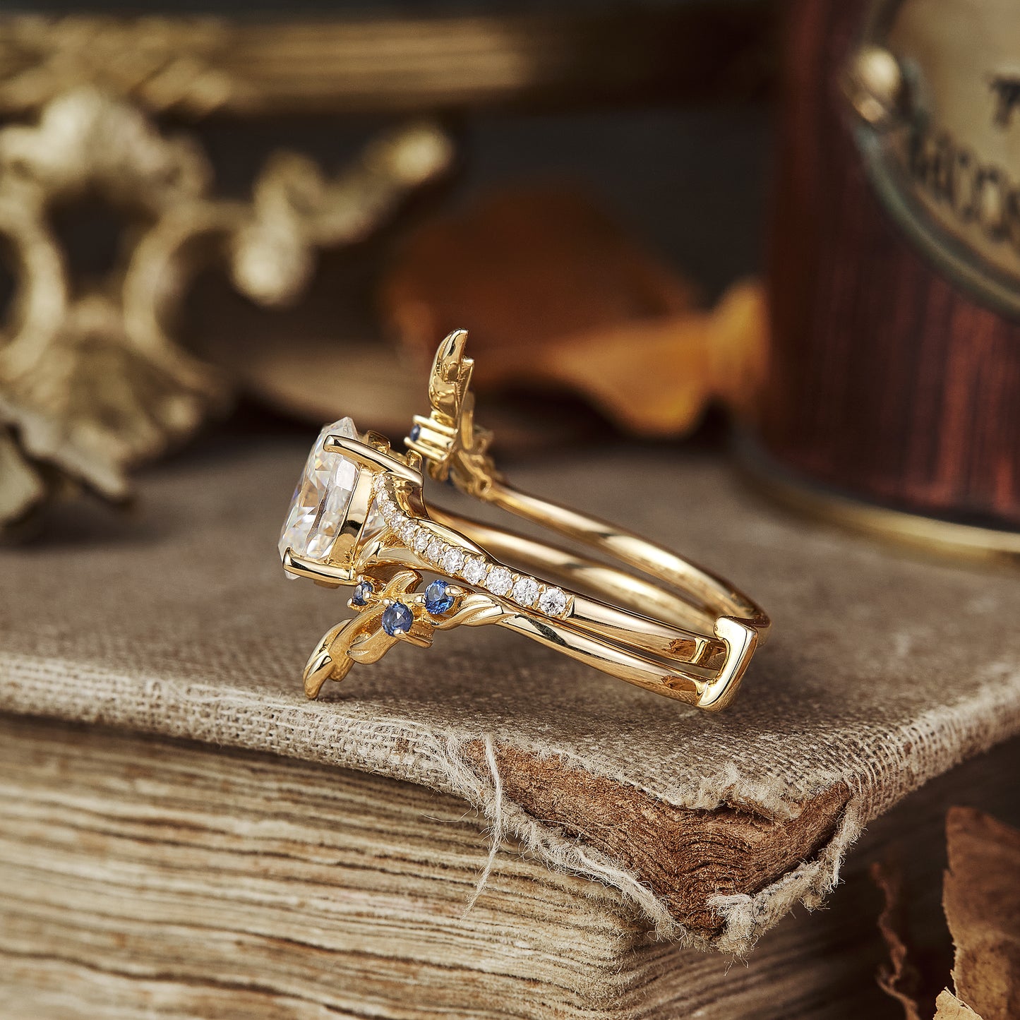 Moissanite engagement ring with leaf design and sapphire accents, set in gold