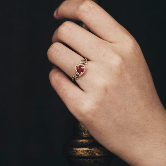 Delicate Blooming Rose ring with ruby, showcased on hand holding candlestick.