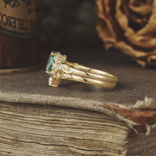 Leaf-inspired gold ring with pear-cut green sapphire and a single moissanite gem.