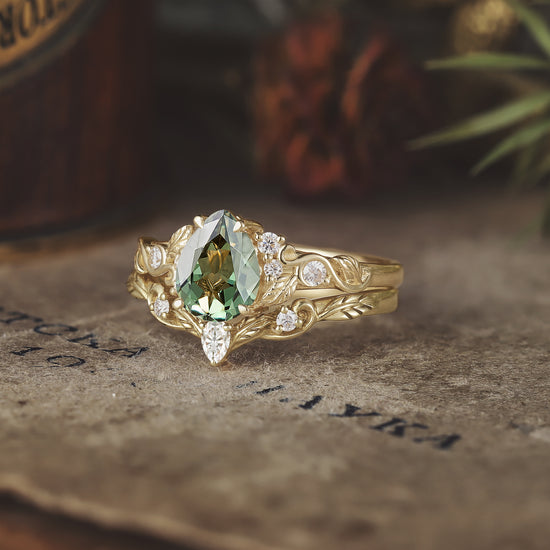 Gold ring set with pear-shaped green sapphire and sparkling moissanite accents.