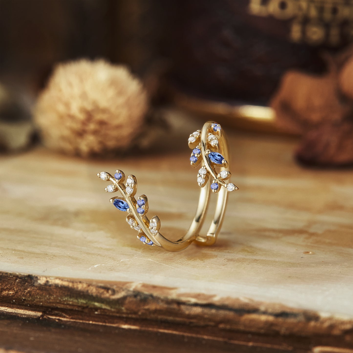 Nature-inspired gold wedding band featuring sapphire and moissanite leaf accents.