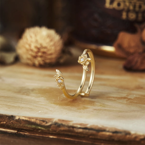 Delicate gold wedding ring with floral motifs and round moissanite accents.