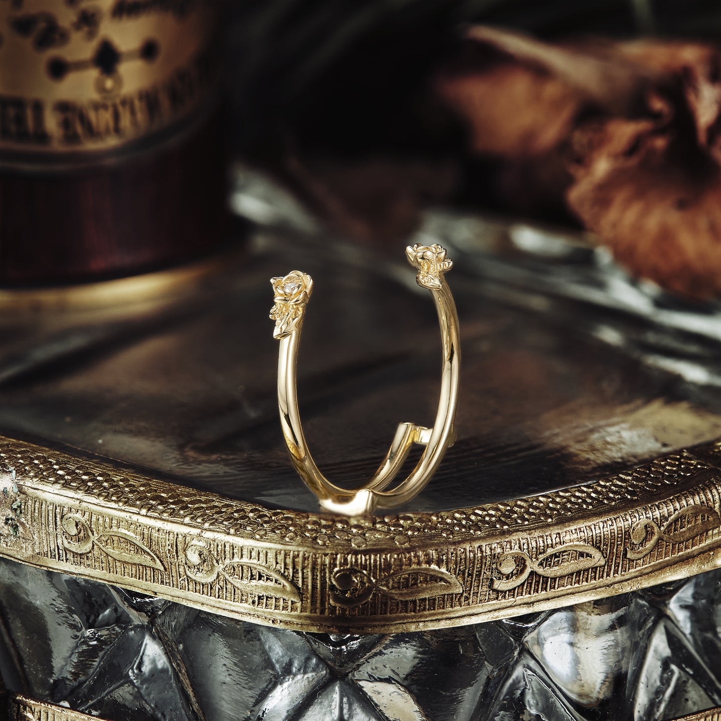 Nature-inspired gold wedding ring with floral motifs displayed on reflective surface.