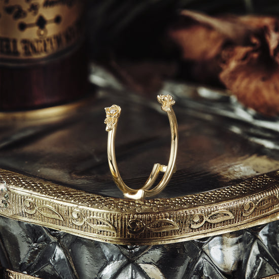 Nature-inspired gold wedding ring with floral motifs displayed on reflective surface.