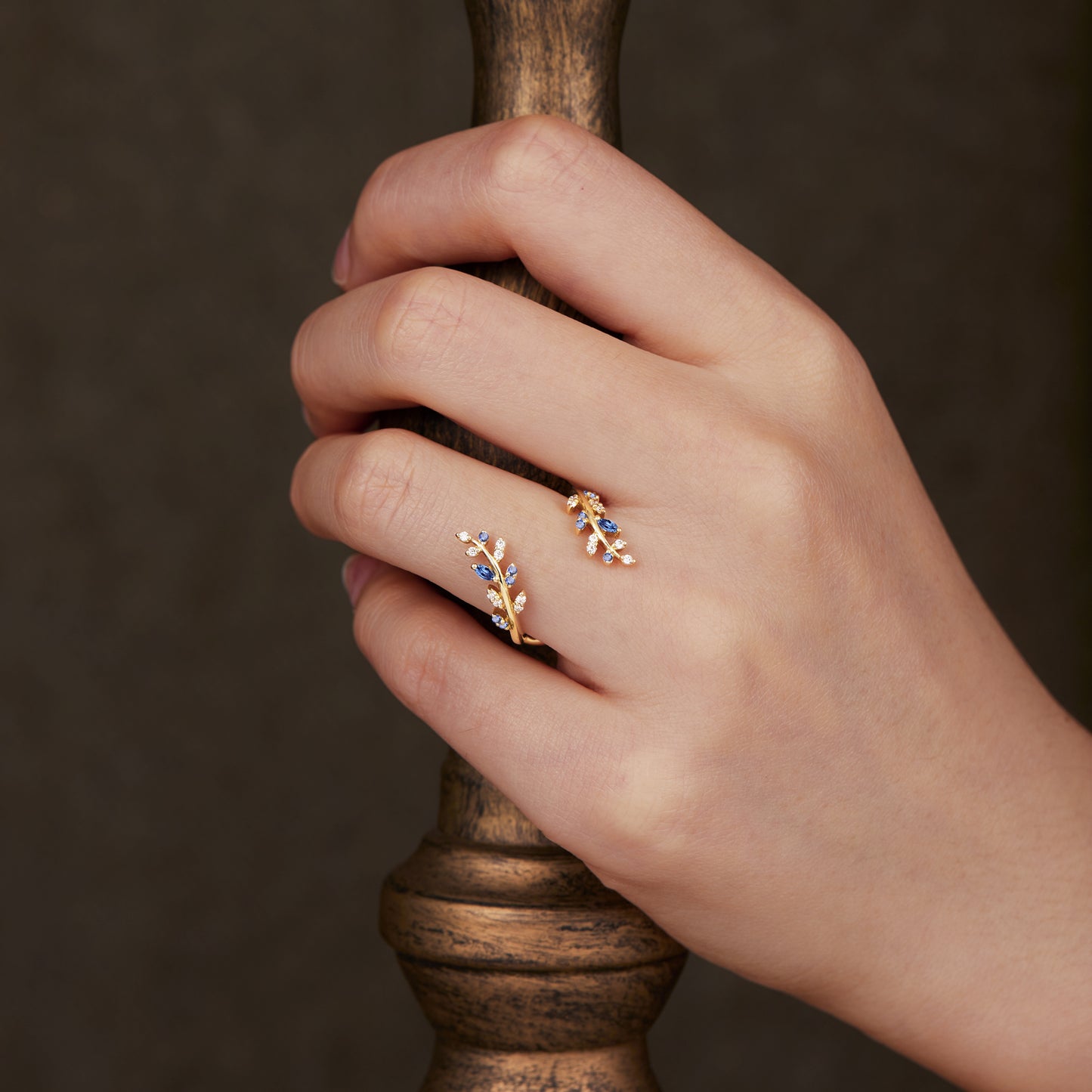 Elegant nature-themed wedding band with sapphire and moissanite on a hand.