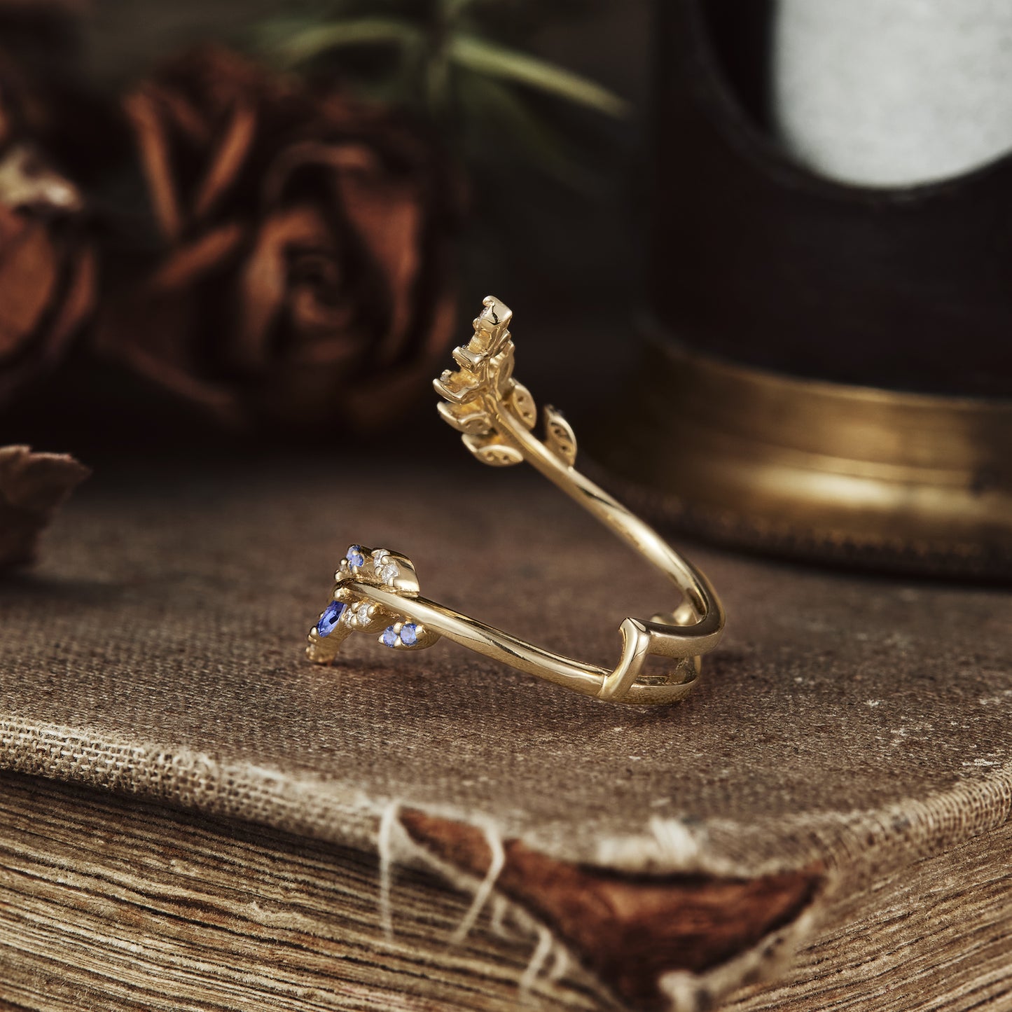 Elegant gold wedding band with leaf design featuring sapphire and moissanite stones.