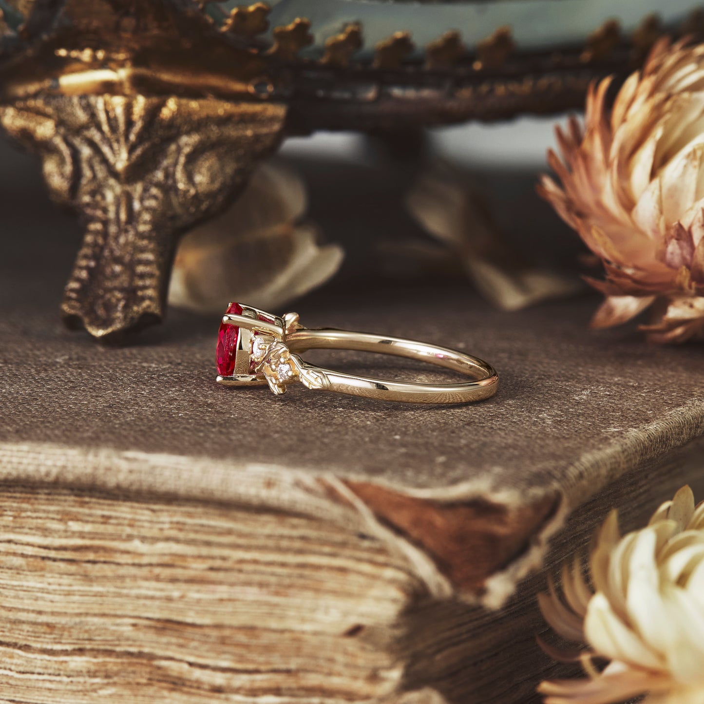 Nature-inspired ruby engagement ring with moissanite accents on a vintage book