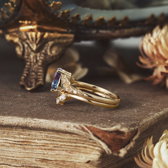 Elegant gold ring set with pear-cut alexandrite and diamond leaf details.