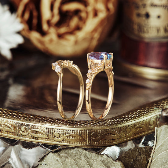 Nature-inspired ring set with pear-cut alexandrite and diamond accents on a decorative tray.