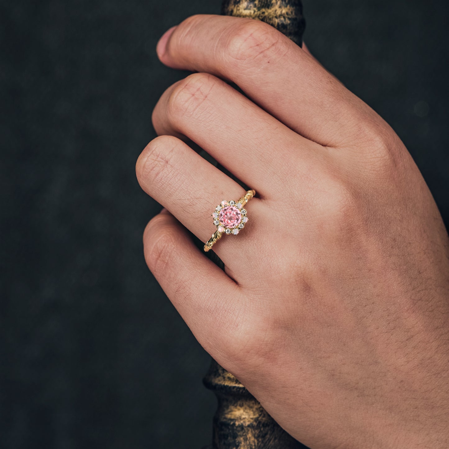 Close-up of hand wearing halo pink Padparadscha ring with moissanite accents.