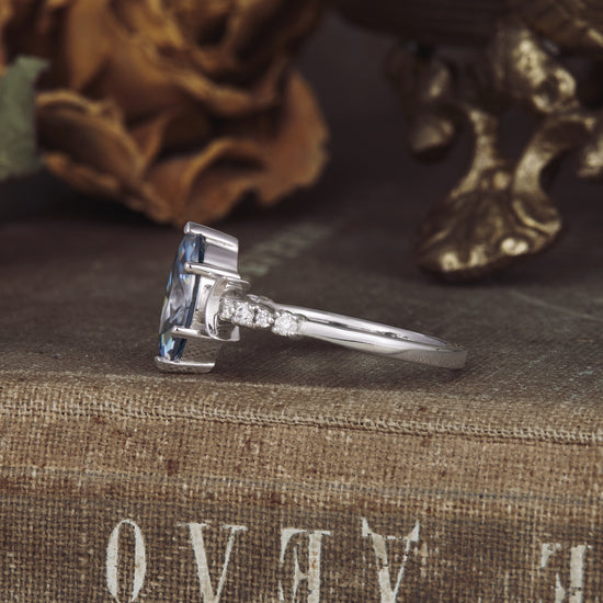 Side view of marquise gray moissanite engagement ring with round cut side stones