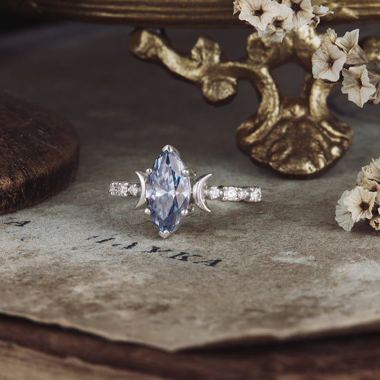 Elegant marquise gray moissanite ring with round side stones on vintage paper backdrop