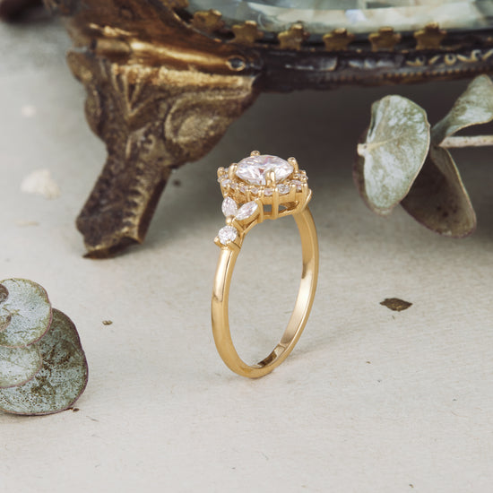 Elegant gold moissanite halo engagement ring with round center stone and delicate side accents.