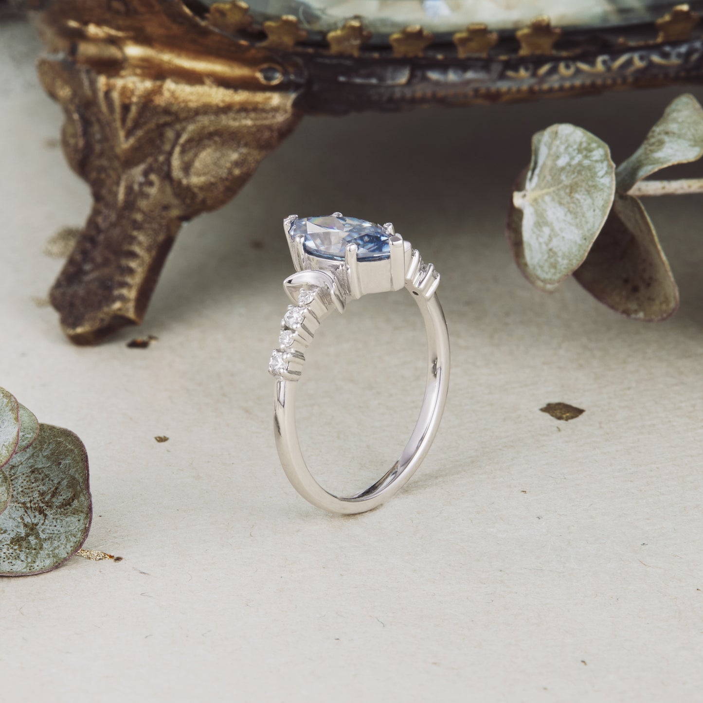 Side view of elegant gray moissanite marquise engagement ring with floral details.