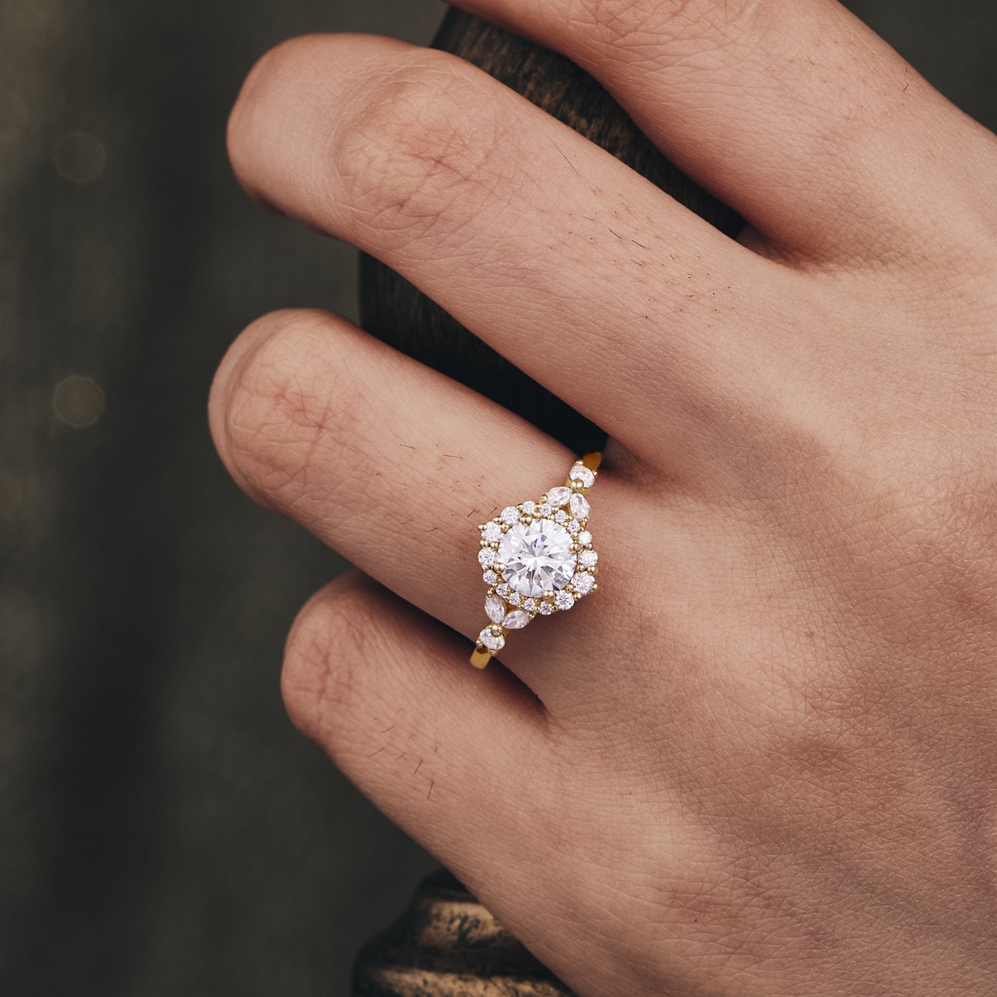 Moissanite halo engagement ring with floral details on hand, gold band shining elegantly.