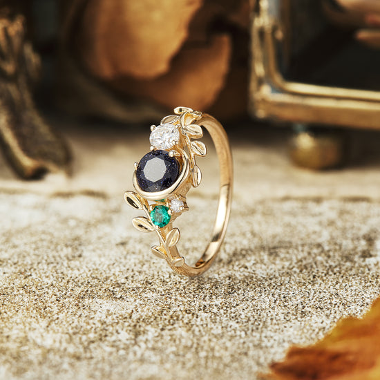Leaf-inspired gold ring with star sandstone, moissanite, and emerald gemstones.