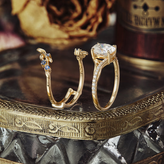 Moissanite twisted leaf ring set with sapphire accents in gold on decorative tray