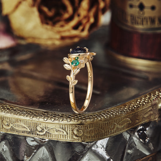 Gold ring featuring star sandstone, emerald, and nature-inspired leaf design.