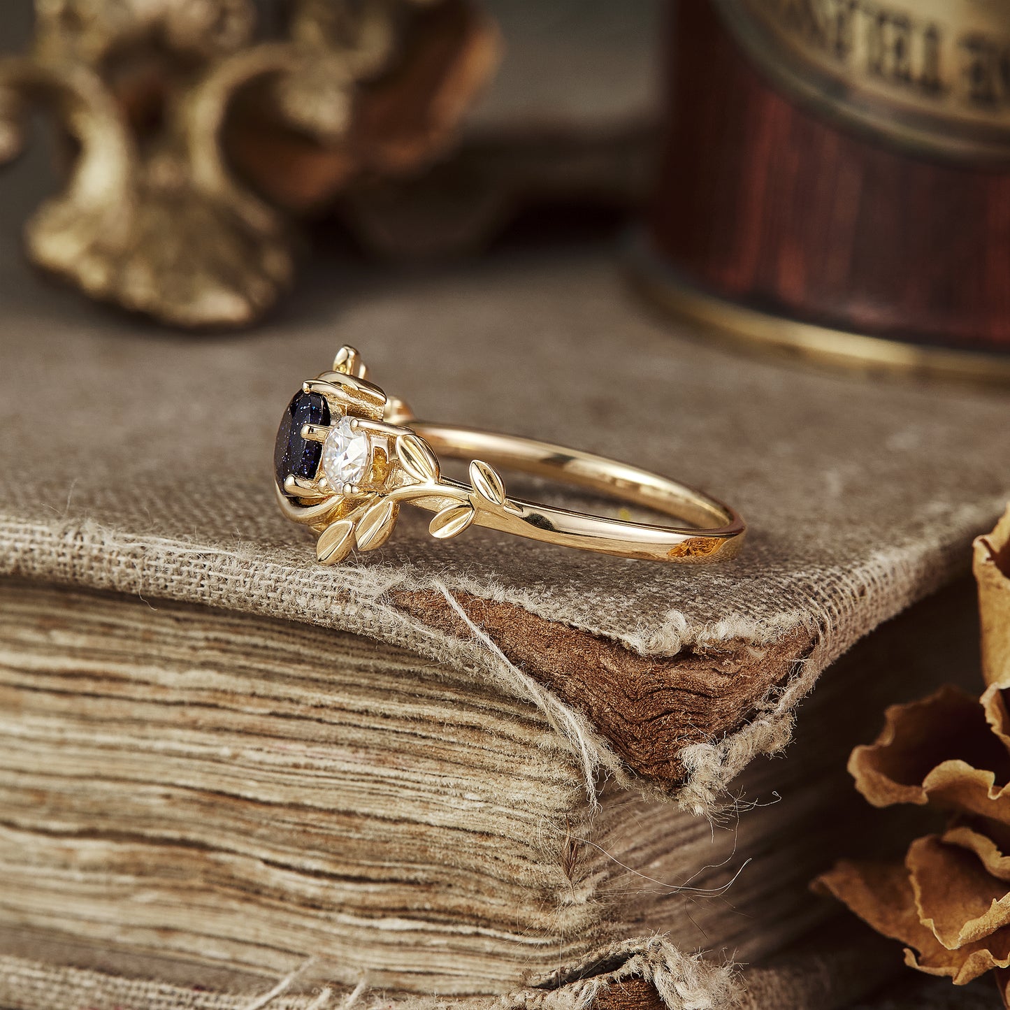 Gold leaf-inspired ring with star sandstone, moissanite, and emerald gemstones.