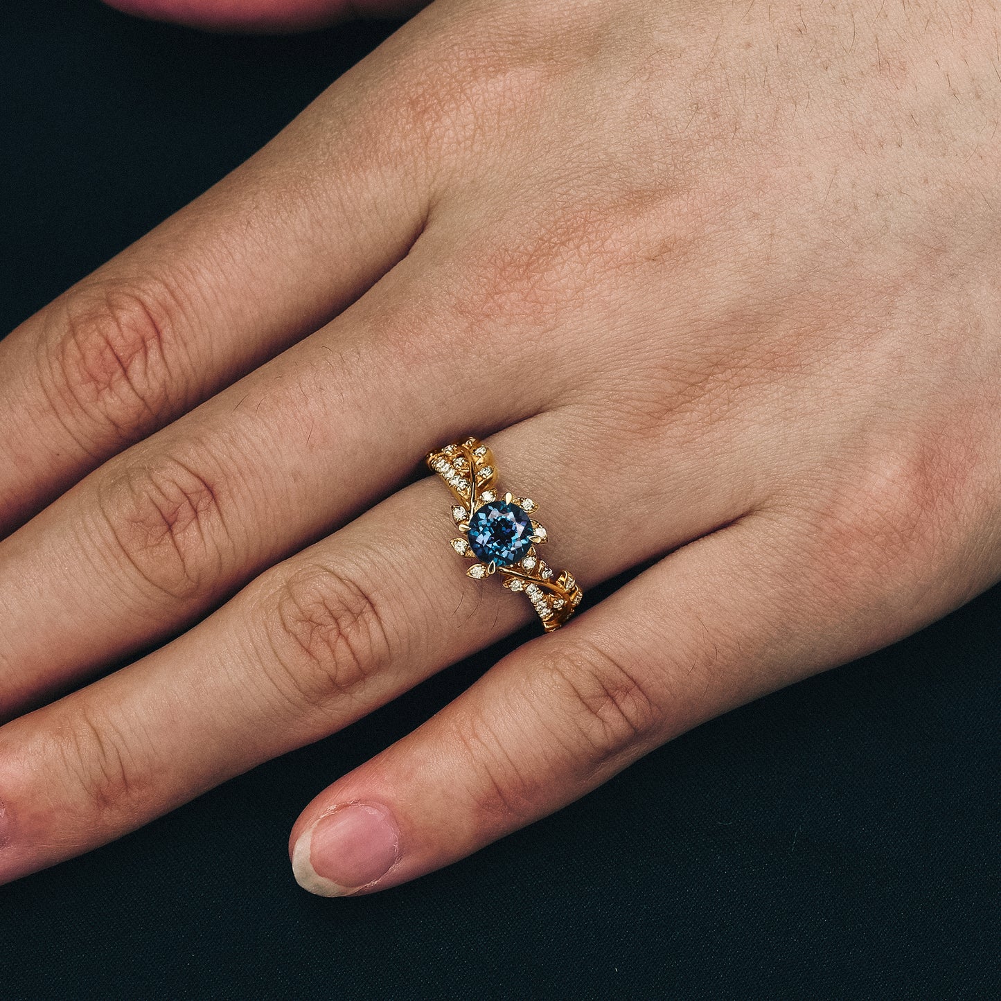 Close-up of gold windmill inspired engagement ring with lab alexandrite and moissanite.