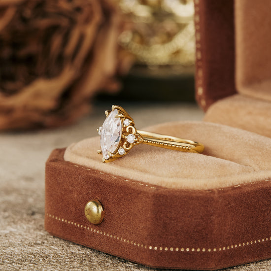 Moissanite marquise ring in gold setting with floral design and side stones