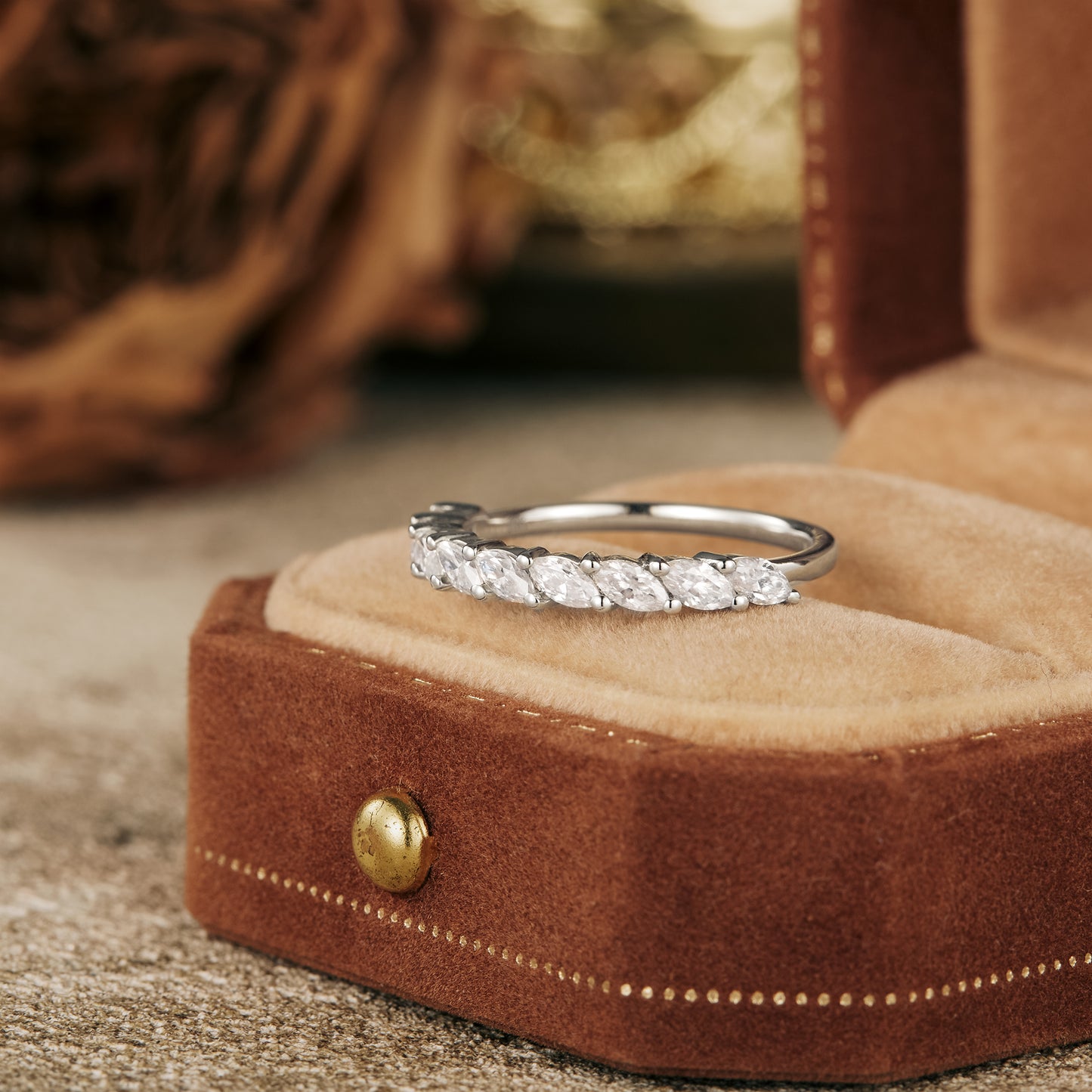 Elegant marquise moissanite wedding band in velvet ring box on rustic surface