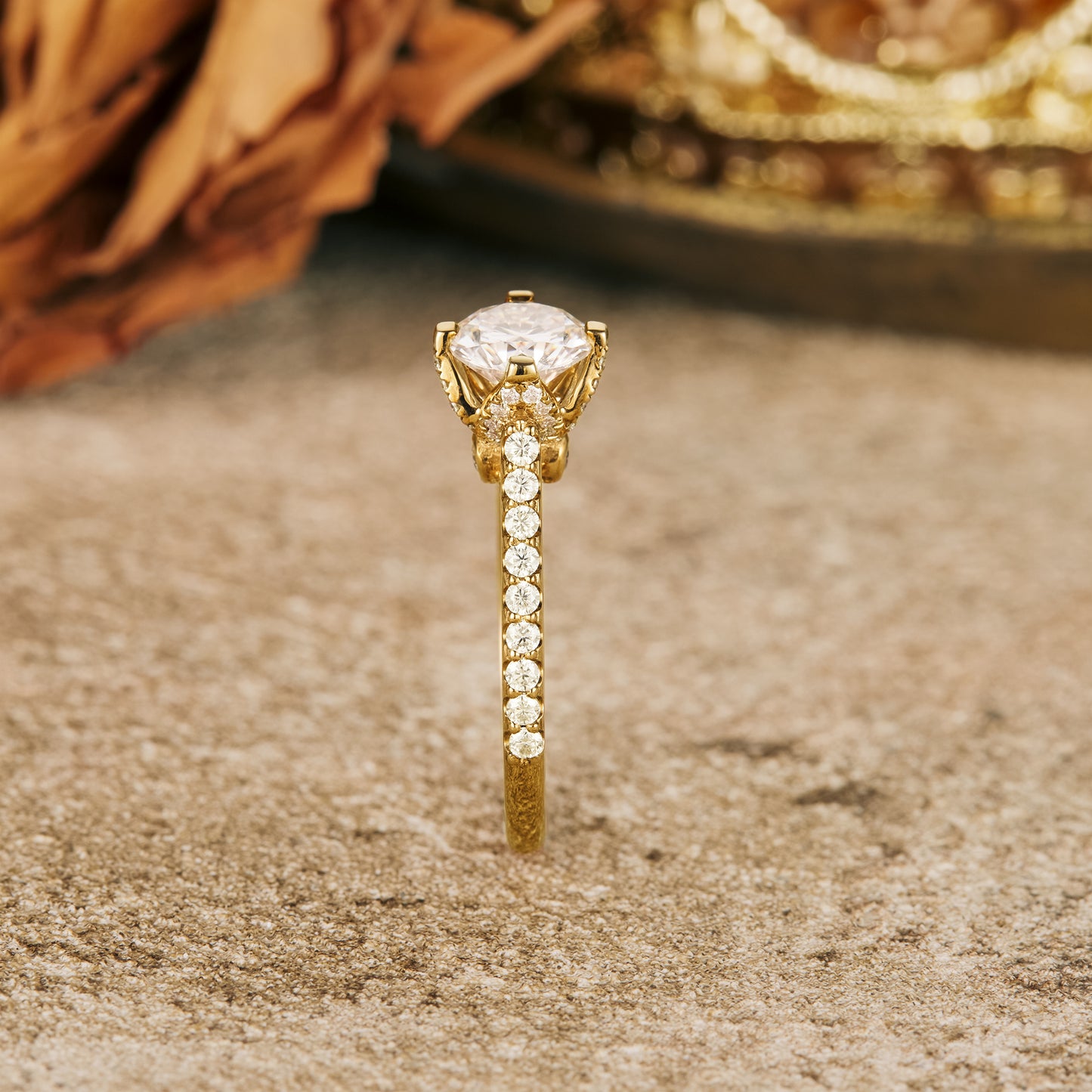Moissanite engagement ring with round stone and shimmering gold band on a rustic surface