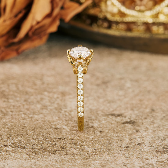 Moissanite engagement ring with round stone and shimmering gold band on a rustic surface