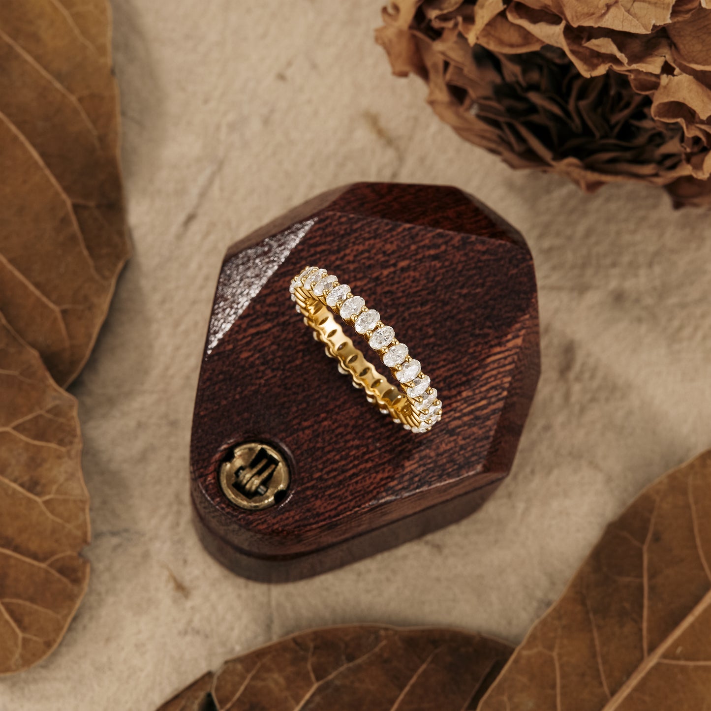 Moissanite oval eternity wedding band on wooden display with nature-inspired decor