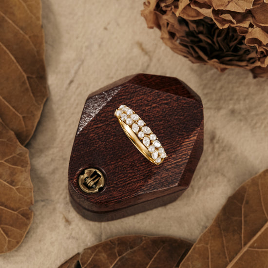 Gold wedding band with moissanite stones, elegantly displayed on a wooden box.