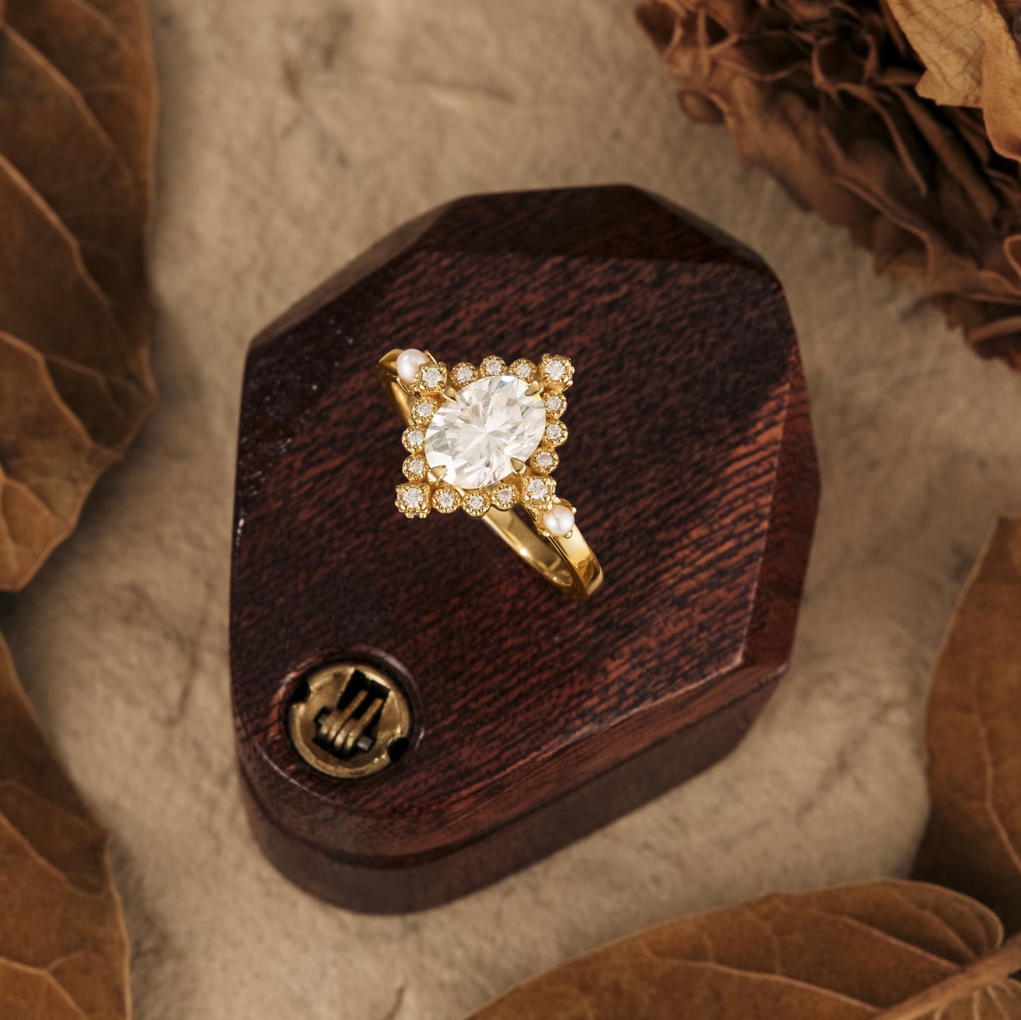 Moissanite ring with round center and halo on wooden ring box, nature-inspired setting.