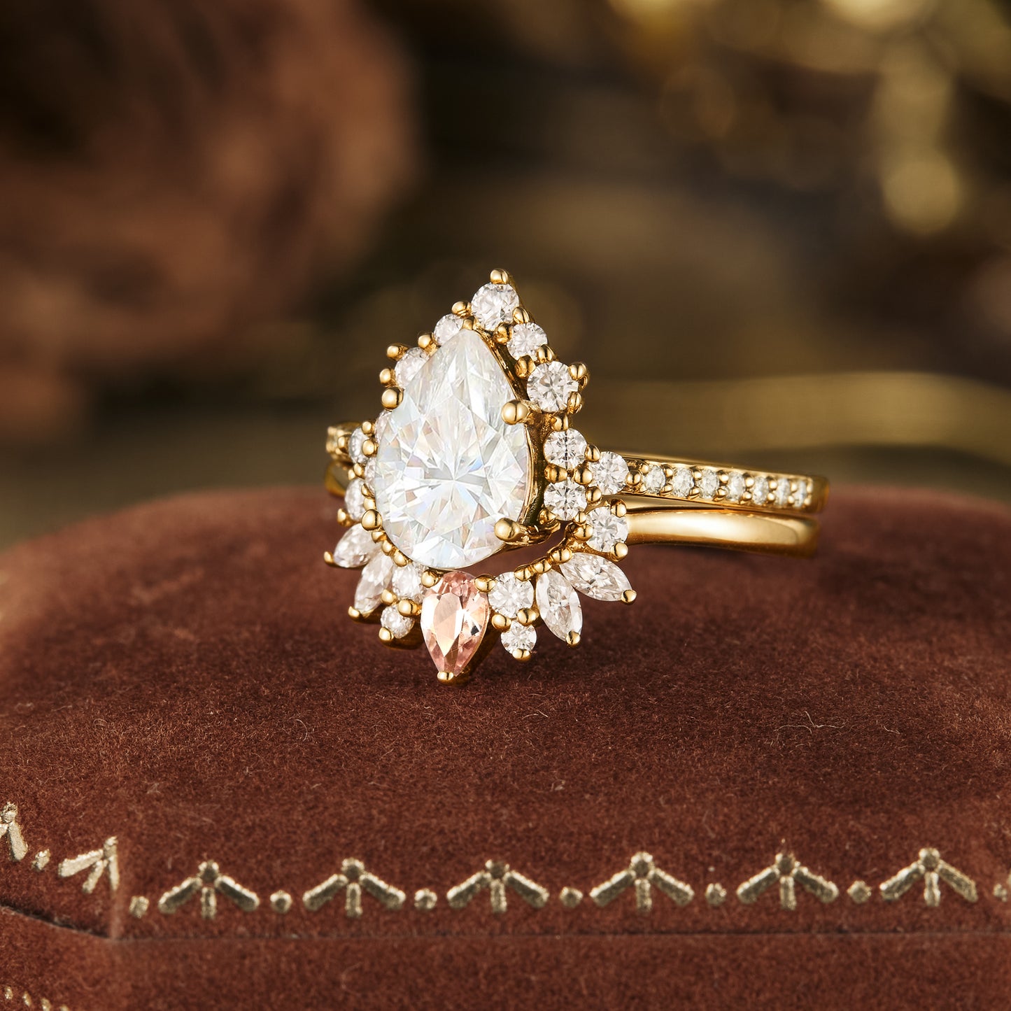 Elegant Moissanite pear ring with halo in gold, displayed on a plush velvet cushion.