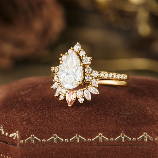 Elegant Moissanite pear ring with halo in gold, displayed on a plush velvet cushion.