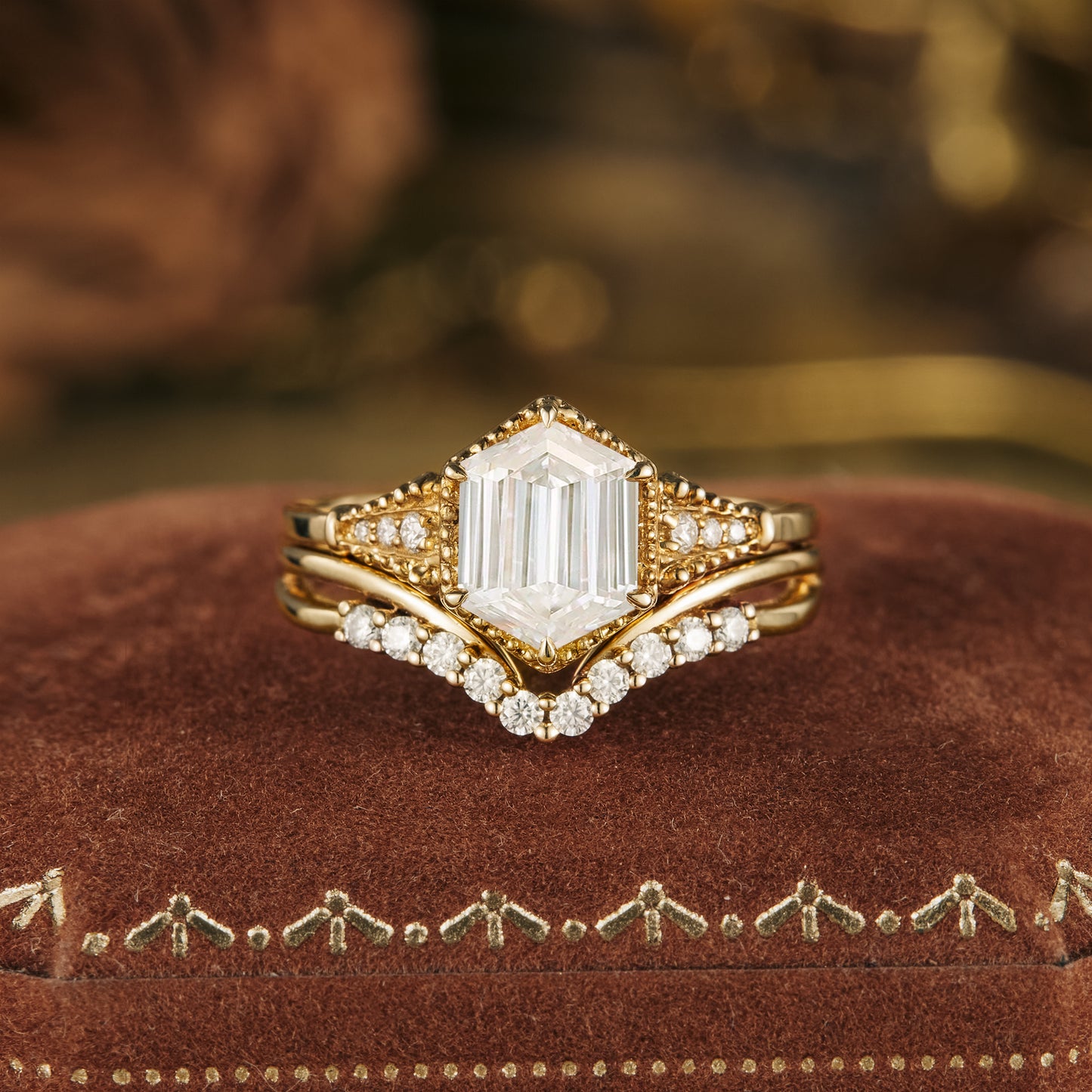 Long-hexagon Moissanite ring set with gold band on velvet surface