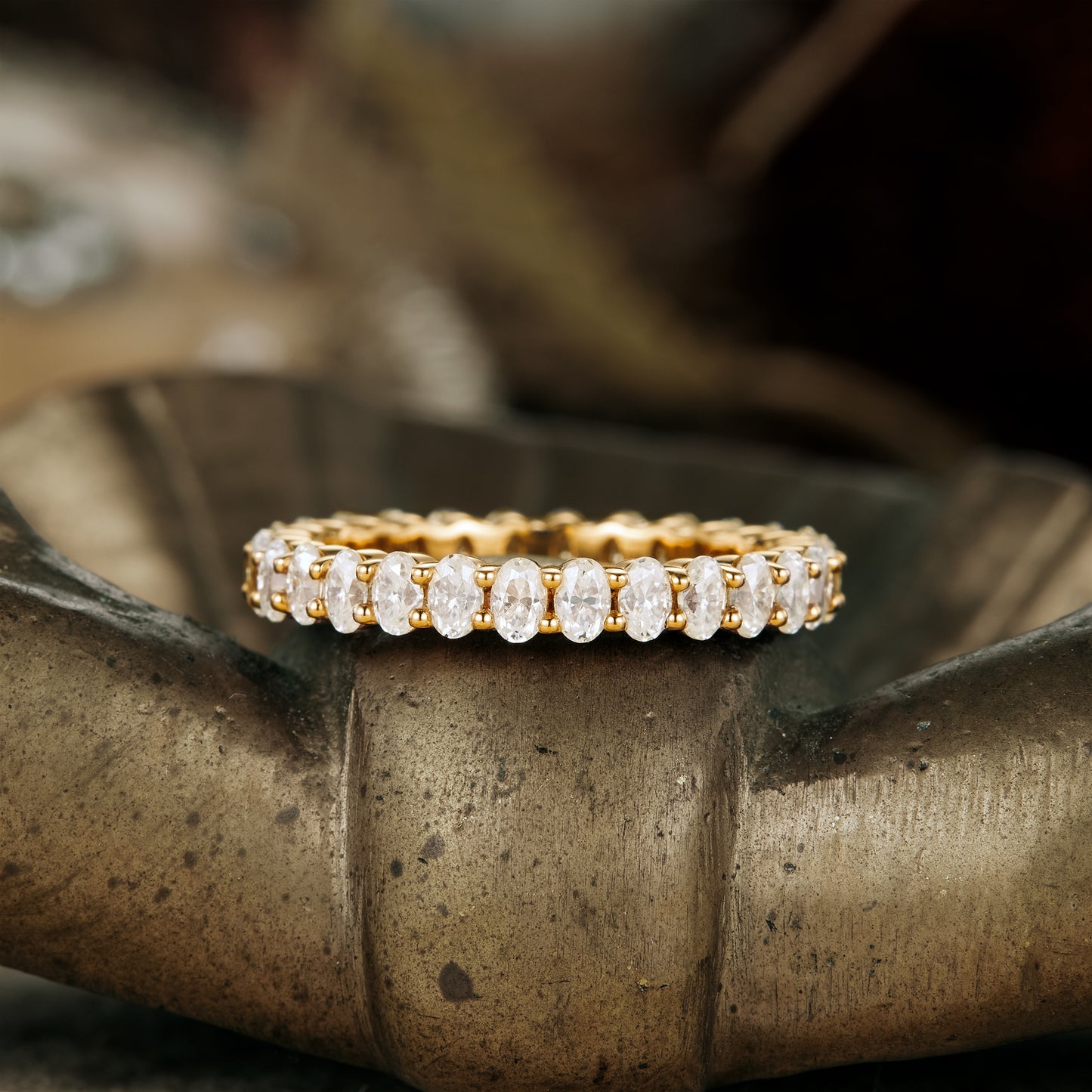 Gold moissanite oval eternity wedding band on a decorative surface