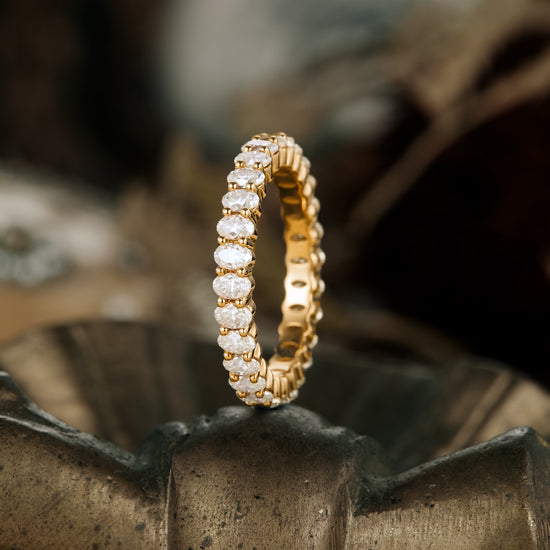 Elegant gold moissanite eternity band showcasing sparkling oval-cut stones.
