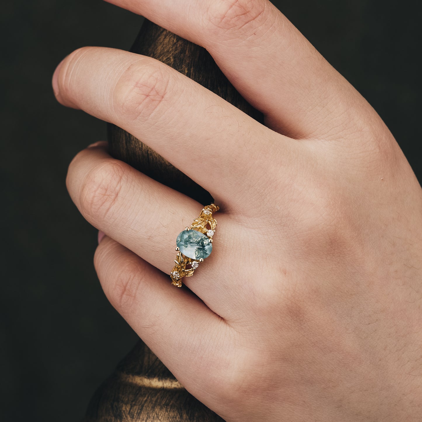 Aquamarine engagement ring on a hand, featuring a leaf-themed gold band.