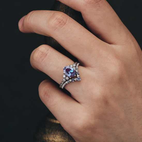 Elegant engagement ring set featuring oval Alexandrite and moissanite on a hand.