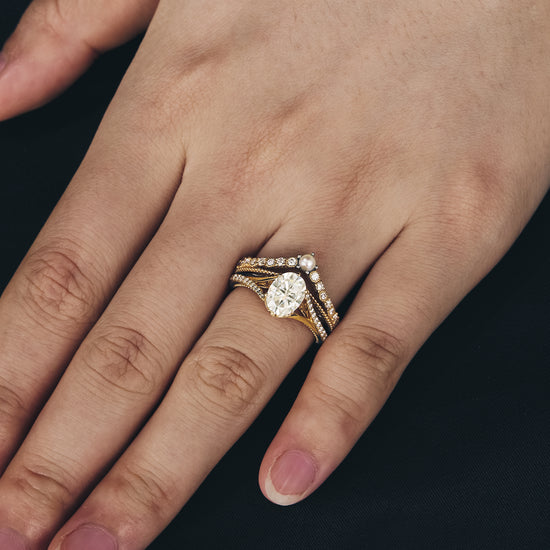 Moissanite peekaboo ring set worn on hand with twisted gold bands.