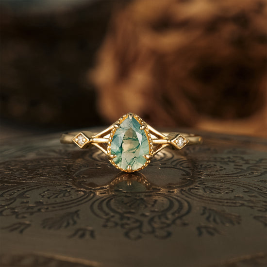 Moss agate pear-shaped engagement ring with gold band and moissanite accents
