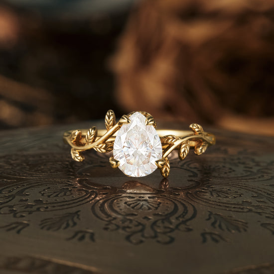 Nature-inspired pear moissanite engagement ring with gold leaf design.